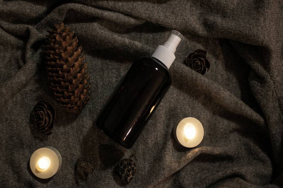 Elegant glass bottle of golden body oil with dried botanicals on marble